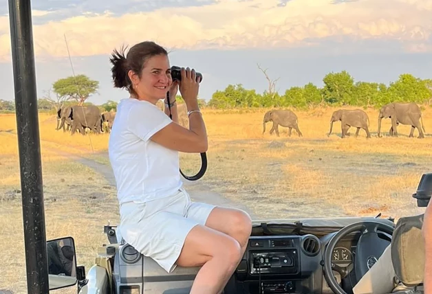 Samantha mirando elefantes africanos a través de unos prismáticos.