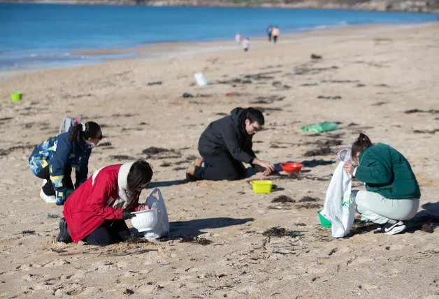 Voluntarios limpiando las playas, tarea complicada a causa del diminuto tamaño de los pélets.