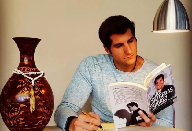 Julián Contreras con su libro sentado en una mesa en casa