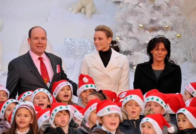 Alberto, Charlene y Estefanía con unos niños cantores en Navidad.