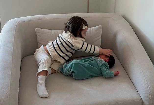 Las hijas de Violeta Mangriñán jugando juntas en un sillón.