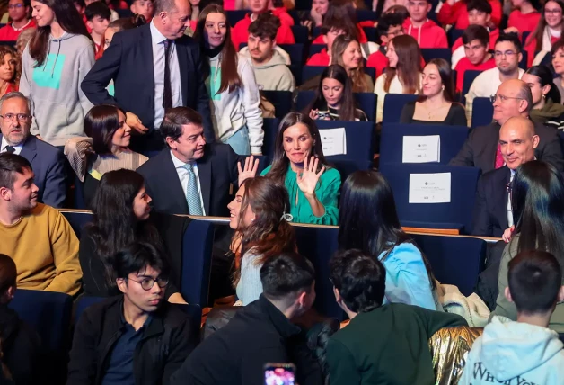 Letizia sentándose y saludando a unos jóvenes en un auditorio