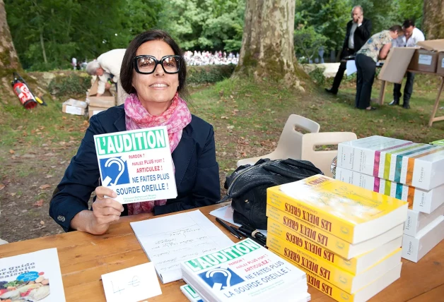 Françoise con un cartel de un programa de su fundación y firmando ejemplares de los libros que ha escrito.