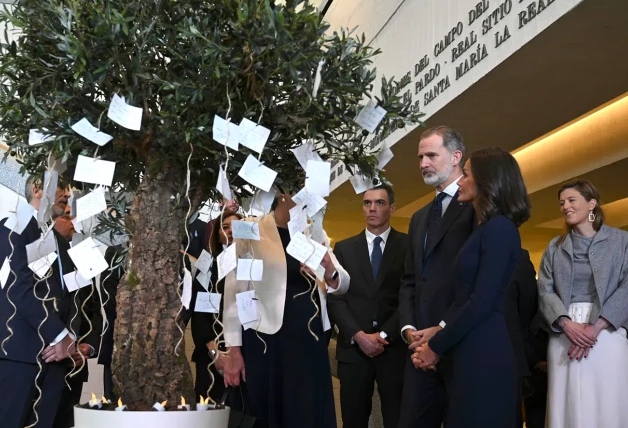 Los Reyes Felipe VI y Letizia y Pedro Sánchez viendo un árbol con dedicatorias a las víctimas.