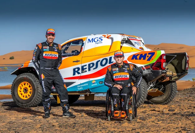 Isidre Esteve posa en silla de ruedas junto a su compañero delante del coche con el que van a competir en el Dakkar.