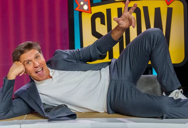 Manuel Díaz, sonriente y tumbado sobre la mesa de 'El show', programa del que es presentador.