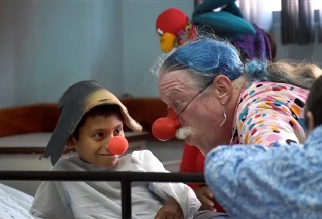 Patch Adams jugando con un niño en un hospital.