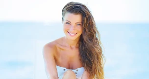 Chica en bañador con el pelo mojado delante del mar