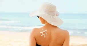 Mujer tomando el sol con una pamela y un sol de crema solar pintado en el hombro.