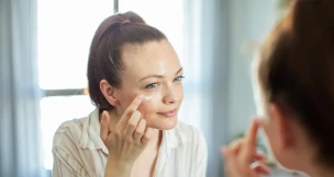 Mujer poniendose crema en los ojos