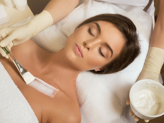 Woman in beauty salon with moistering mask applied on decollete zone