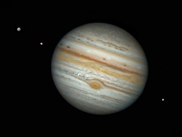 Una impactante foto del planeta Jupiter con tres de sus lunas más grandes.