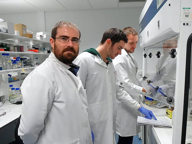 Investigador Asier Unciti con sus compañeros científicos en un laboratorio.