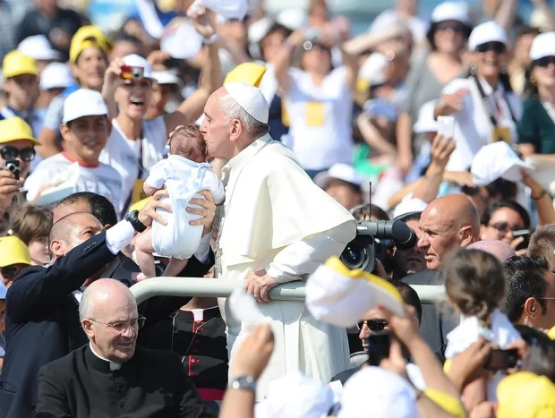 El Papa Francisco besando la cabeza de un bebé rodeado de gente en Lampedusa.