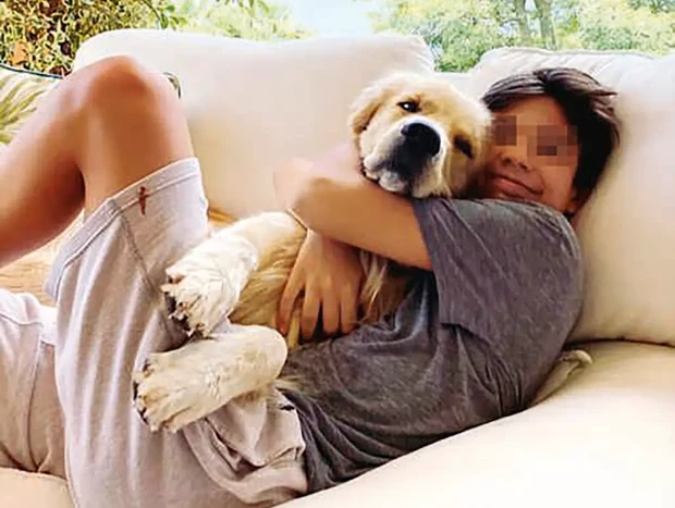 Guillermo Iglesias abrazando a un perro en el sofá.