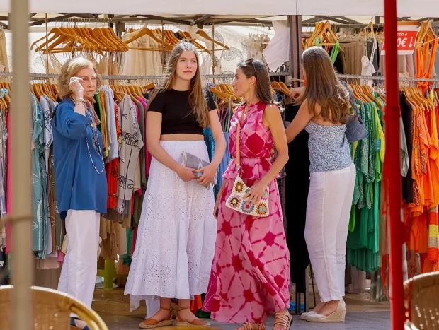 Letizia con sus hijas y la reina sofía mirando vestidos en un mercadillo de Mallorca.