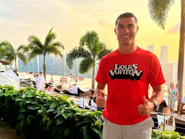 Cristiano Ronaldo posando ante unas palmeras haciendo la señal de ok