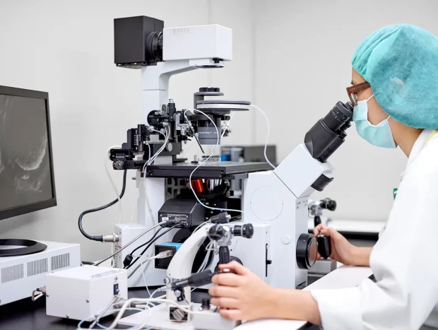 Científica trabajando ante un microscopio en un laboratorio