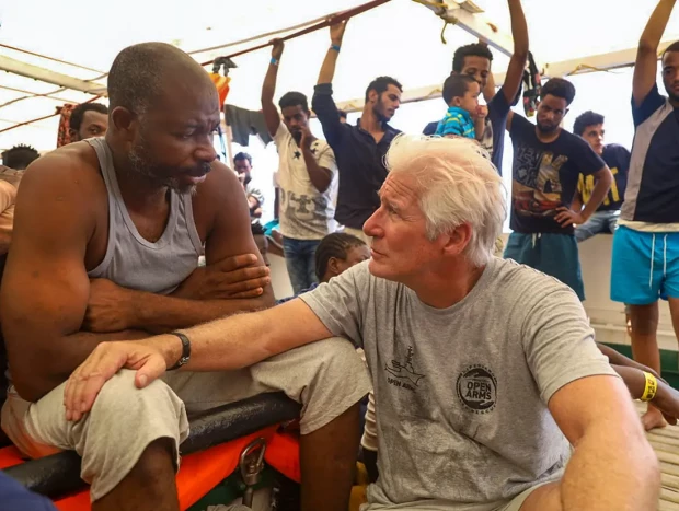 Richard Gere hablando con un hombre de origen africano rescatado por la ONG Open Arms