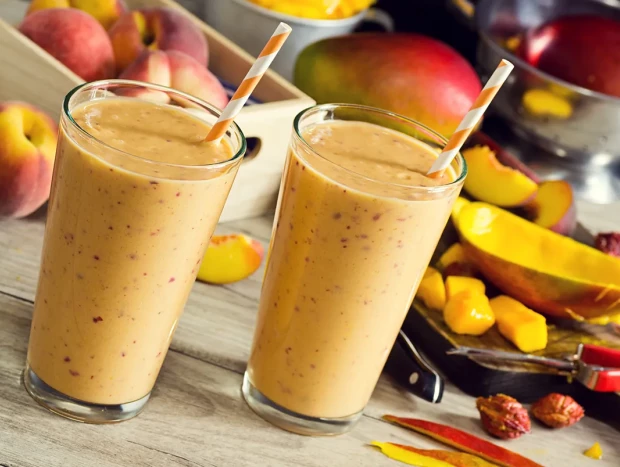 Batido de mango y melocotón servido en vaso con textura cremosa y color vibrante
