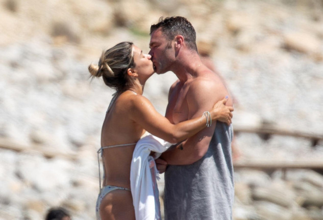 La pareja, dándose un tierno beso en la playa.
