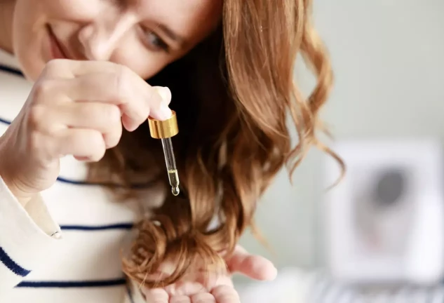 Mujer joven cuida su cabello con aceite cosmético