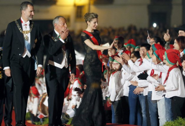 Una guapísima Letizia saluda sonriente a un grupo de niños que la aclama, en presencia de su esposo el Rey y el presidente luso. 