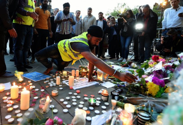 Un hombre de la comunidad india deposita unas flores en un espontáneo homenaje a las víctimas del atentado.