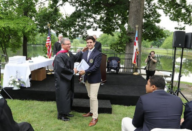 El joven, recogiendo el diploma de graduación.