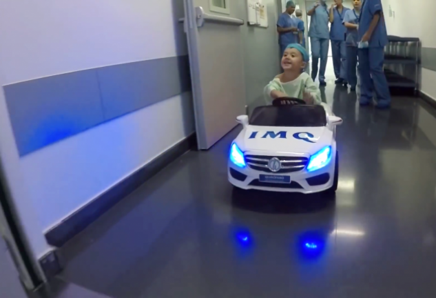 Un paciente infantil se dirige al quirófano en el coche eléctrico que conducen, por control remoto, los sanitarios.