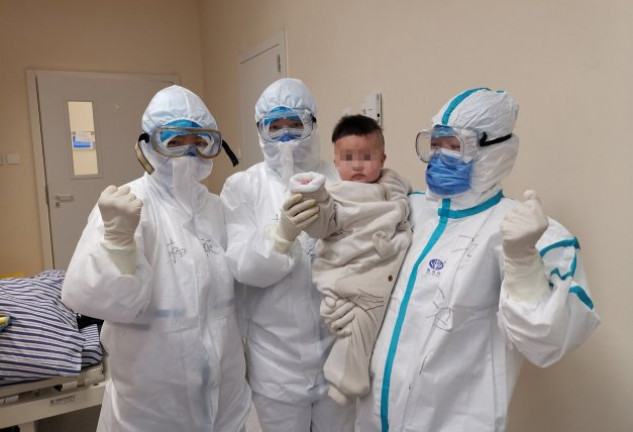 Tres enfermeras, completamente protegidas, con un bebé infectado de coronavirus en un hospital de China.