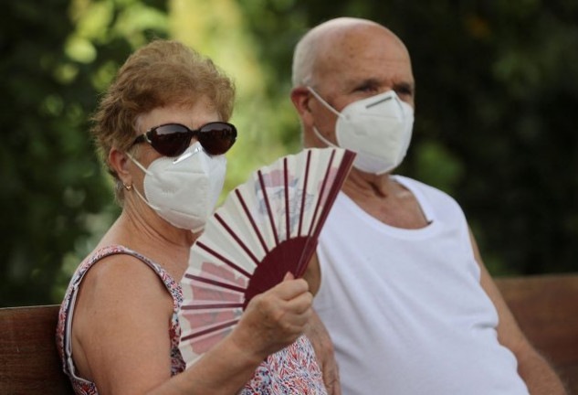 Una pareja de personas mayores toman el aire en un banco.