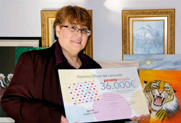 Matilde, de 56 años, con el diploma del premio. Detrás, los cuadros que pinta y que decoran su casa.