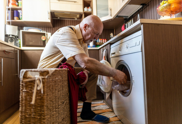 Un hombre mayor poniendo la lavadora.