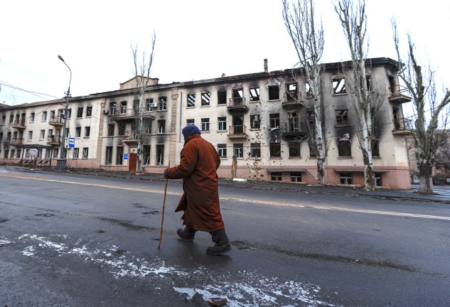 Un hombre paseando ante edificos destruidos por la guerra en Ucrania