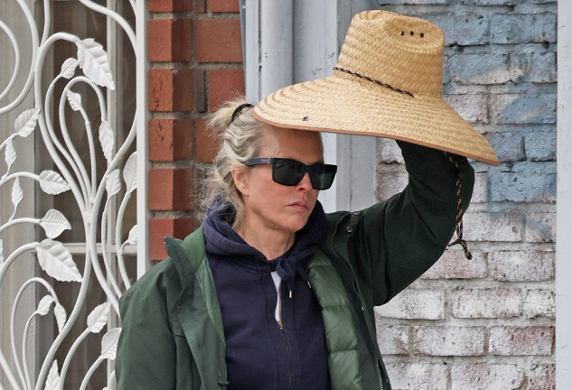 Kim Basinger paseando por la calle con un sombrero en la mano.