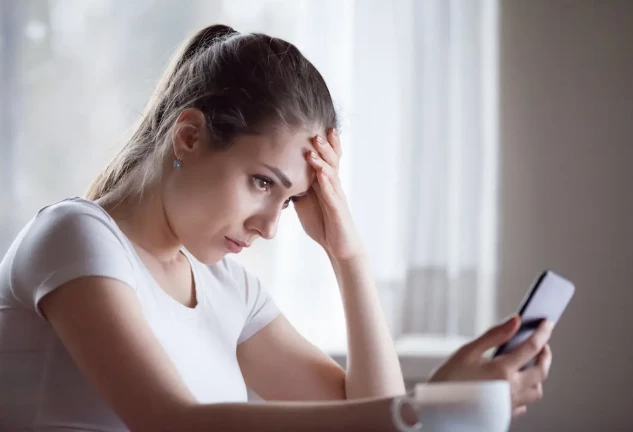 Mujer preocupada mirando la pantalla del móvil.