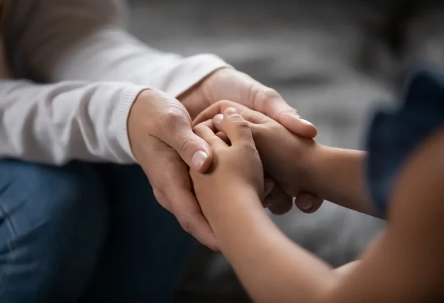 Adulto sosteniendo las manos de un niño.