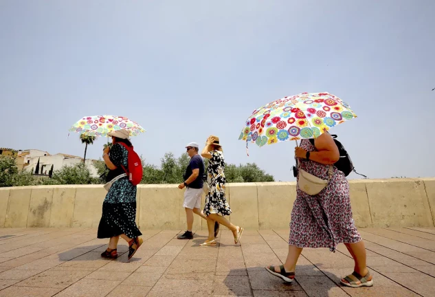 Personas andando a pleno sol con sombrillas