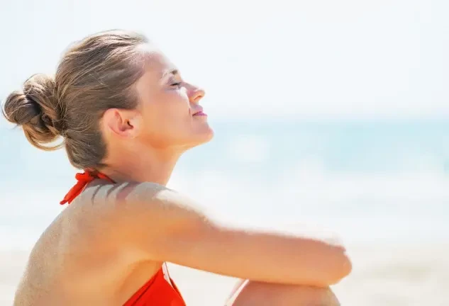 Mujer tomando el sol en la playa y recibiendo vitamina D de forma natural