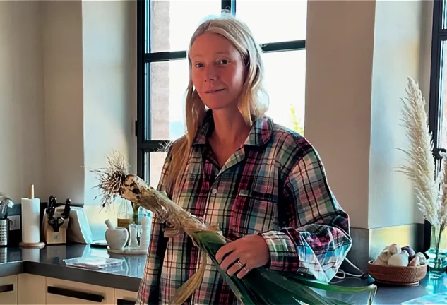Gwyneth Paltrow con un puerro gigante en la mano, en su cocina.
