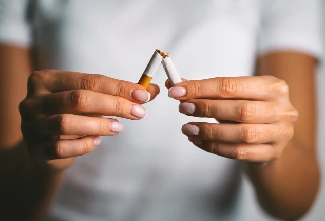 Manos de mujer rompiendo un cigarrillo por la mitad.