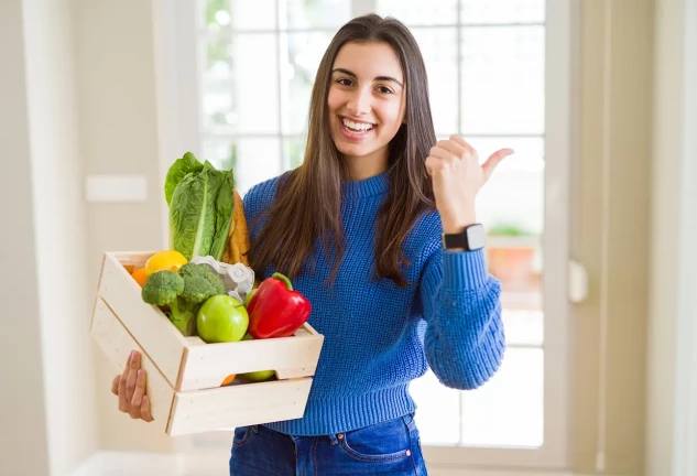 Chica sonriente con una cesta de vegetales en la mano