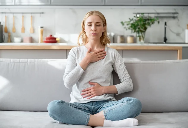 Mujer sentada en un sofá intentando calmar su ansiedad.