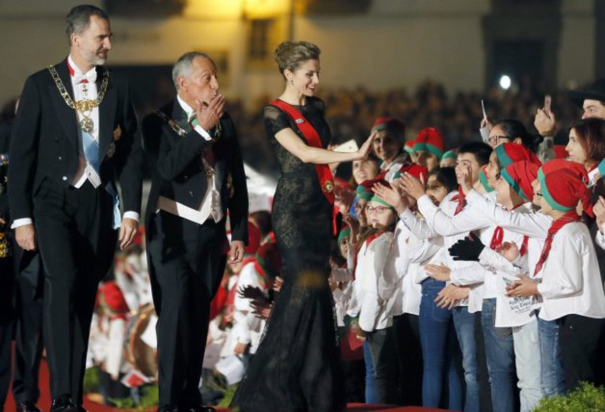 Una guapísima Letizia saluda sonriente a un grupo de niños que la aclama, en presencia de su esposo el Rey y el presidente luso.