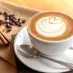 Taza de café con granos de café con leche y varillas de canela