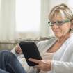 Mature woman using tablet computer while relaxing on sofa at home