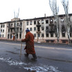 Un hombre paseando ante edificos destruidos por la guerra en Ucrania