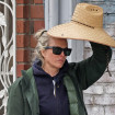 Kim Basinger paseando por la calle con un sombrero en la mano.