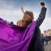 Mujer con una capa morada y el puño en alto